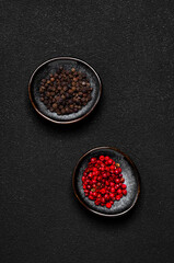 Black and pink rose peppers in small bowls. Black table top view