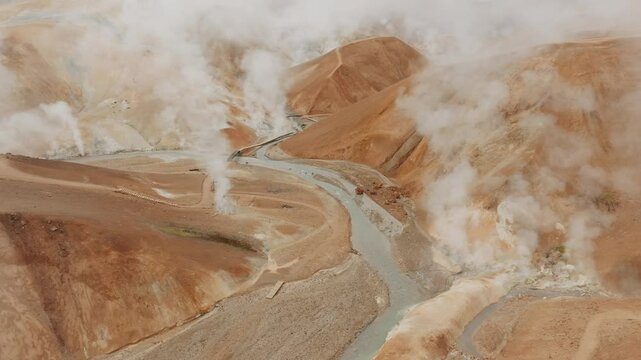 50fps aerial shot of Kerlingarfj&ouml;ll&rsquo;s geothermal hills. Steam vents and winding rivers create a surreal landscape of orange and green hues. Perfect for nature, travel, and adventure projects.