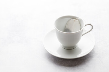 Cup of hot tea with tea bag on white table background.