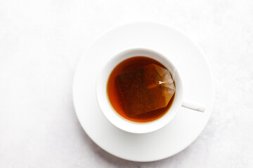 Cup of hot tea with tea bag on white table background.