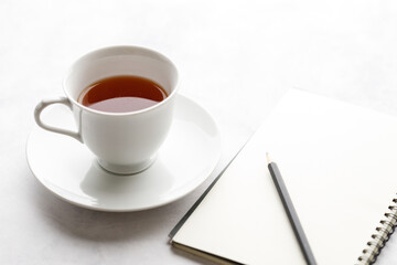 Cup of hot and notebook with pencil on white table background. Study time concept.
