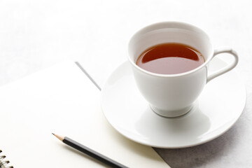 Cup of hot and notebook with pencil on white table background. Study time concept.