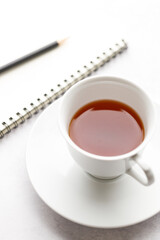 Cup of hot and notebook with pencil on white table background. Study time concept.