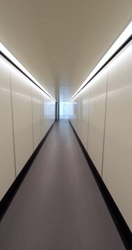 Walk through modern jetway with white walls from passenger plane after landing at destination, first person view vertical shot. Deboarding last of first - no people visible ahead