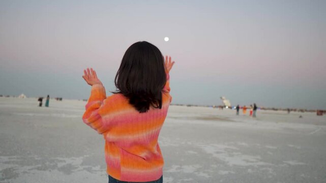 Indian tourist girl vlogging at Rann Utsav at White desert of Kutch and showing full moon in sky at Kutch, Gujarat, India. Happy traveler sharing her experience in social media. Travel content creator