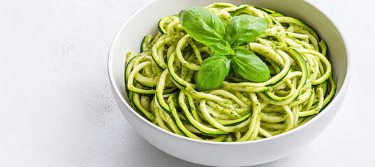Zucchini noodles with pesto sauce garnished with fresh basil