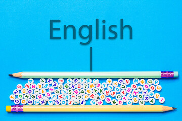 Pencil and English letters placed on blue background, beginning concept of reading, writing, learning English.
