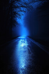 A close-up of wet asphalt at night, glistening with reflections of deep blue light, surrounded by mist and subtle fog for a cinematic and mysterious look 