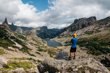 A male tourist looks at the mountains while standing at the top