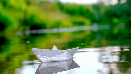 Paper boat on the water in the sun's rays