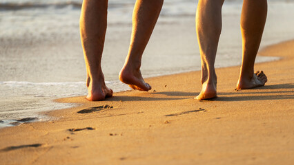 Young people walking on a sandy beach barefoot