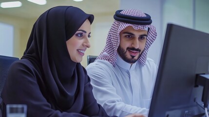 A professional setting featuring a man and woman collaborating on a computer, showcasing teamwork and modern workplace dynamics.