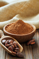 cocoa powder in bowl and cocoa beans in scoop on table