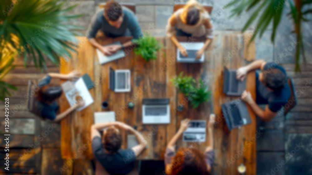 Poster Blurry Group of diverse professionals collaborating in a modern coworking space working on laptops and documents together engaged in team discussion brainstorming