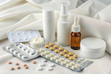 A collection of medical supplies including pills, drops, and creams, scattered on a white fabric surface.