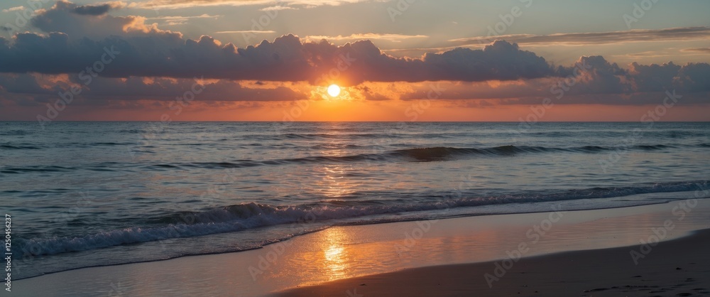Poster serene sunset over ocean waves reflecting on sandy beach with cloudy sky in the background ideal for