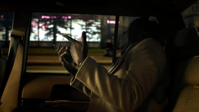 Black rapper flowing in backseat of taxi, cool African guy singing his own songs . Talented rapper, African American male person riding by car in city in night, nightlife in megapolis, diversity