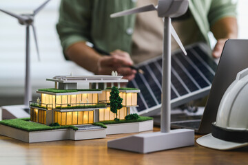 Modern eco-friendly house model with Energy Design Engineer holds solar panels in background with...