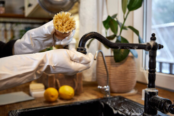 woman washes black kitchen faucet with wooden brush, eco-friendly cleaning