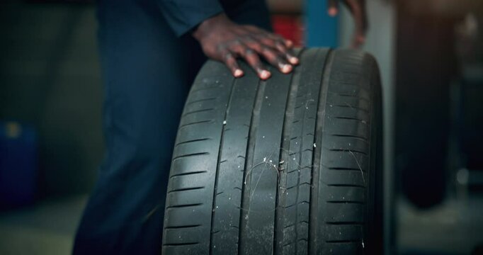 Black man, mechanic or change tire on car for repair service, maintenance or fix in professional garage. Hands, workshop or remove wheel of vehicle for inspection, check alignment or transport safety