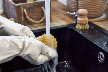 a woman washes a wooden dish brush in a black sink
