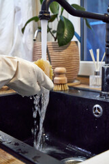 a woman washes a wooden dish brush in a black sink