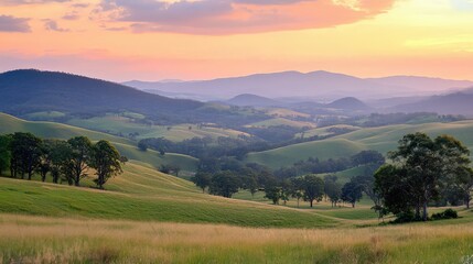 Obraz premium Serene Landscape of Rolling Green Hills Under Colorful Skies at Dusk, Capturing the Natural Beauty of Rural Australia with Soft Light and Peaceful Atmosphere