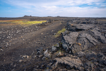 Scenic view of Valahnúkamöl Bay with dramatic cliffs, lava rocks, and the Atlantic waves in Iceland