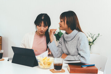 Female higher education student using laptop and studying book in home, Online learning.