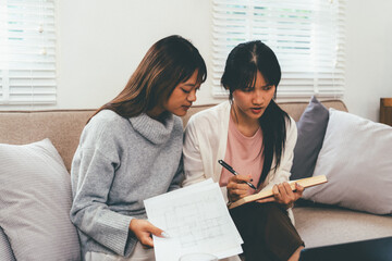 Female higher education student using laptop and studying book in home, Online learning.