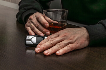 Drunk man lying on the table with a glass of alcohol, car keys on the counter, drunk car driver, drowning his sadness in a glass of whiskey