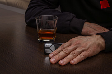 Drunk man lying on the table with a glass of alcohol, car keys on the counter, drunk car driver, drowning his sadness in a glass of whiskey