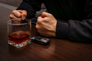 Drunk man lying on the table with a glass of alcohol, car keys on the counter, drunk car driver, drowning his sadness in a glass of whiskey