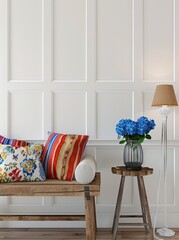 A rustic wooden bench with colorful pillows. a vase of blue flowers on a wooden stool. and a floor lamp against a white paneled wall