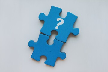 Obraz premium Two blue puzzle pieces with a question mark, symbolizing unanswered questions or incomplete solutions.