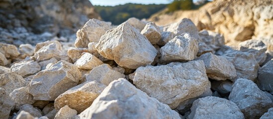 Large irregular lumps of limestone stacked in a natural quarry setting with blurred background of rocky terrain and greenery.
