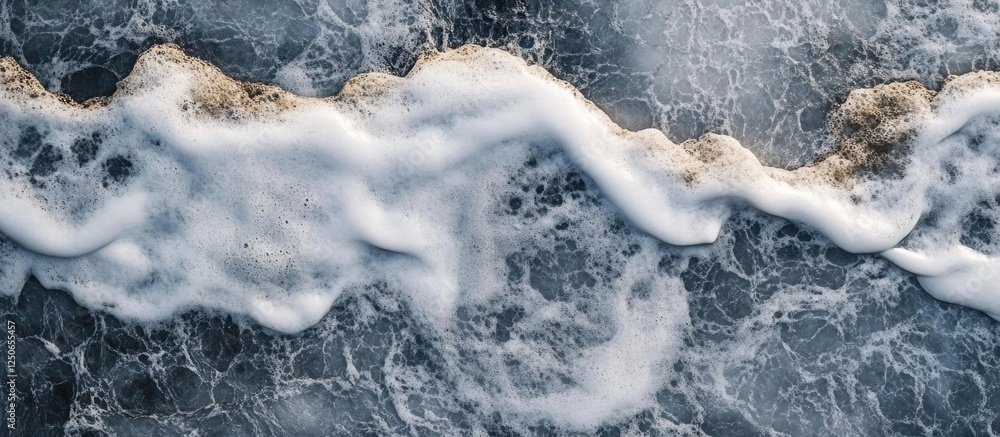 Poster aerial view of waves crashing on rocky shore creating textured abstract patterns in deep blue and wh