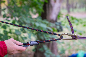 A crossing for sports tourism in the park: a rope is stretched between trees, with carabiners, a...