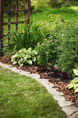 natural stone lawn edging and mulching flowerbeds in summer garden