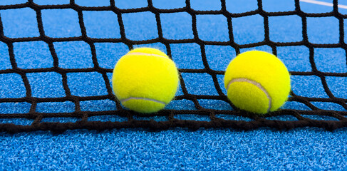  paddle tennis balls near the lines of a blue paddle tennis court, racket sports concept