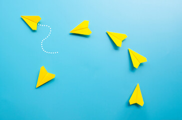 Top view of origami yellow paper airplane with one airplane leaving the group