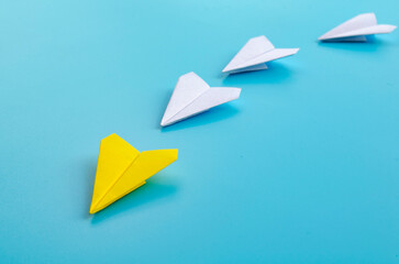 Origami paper airplane with yellow airplane leading the rest of white airplane