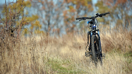 bike stands on in the field. A mountain bike on a field path with dry autumn grass. cycling. outdoor cycling activities. active rest, sports, travel. good for health. recreation, warm season