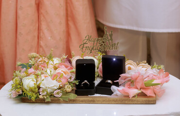 Color roses and engagement ring box styled beside a plate, wedding rings and roses, wedding ring...