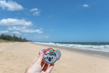 Australia Christmas concept, hand holding festive season cookie at beach, hot summer day, coastal sand and waves