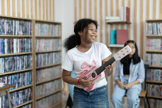 School children education practicing playing the ukulele in classroom. kid schoolgirl happy learning. Writing as instructed by teacher. concept of back to school..