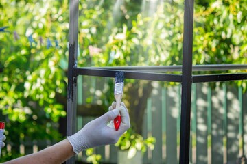 close up of painting metal with brush in garden.