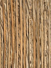 Close-up of a traditional woven palm leaf fence with natural textures and earthy brown tones, showing intricate weaving patterns and weathered details.