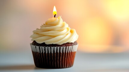 Close-up of a single cupcake with a lit candle, set against a pastel-colored background.