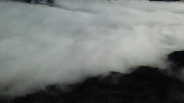At the feet of the mountain, lying a sea of clouds, rolling and swirling like an ocean under a gray and white canvas, in Alpes-Belledonne, France